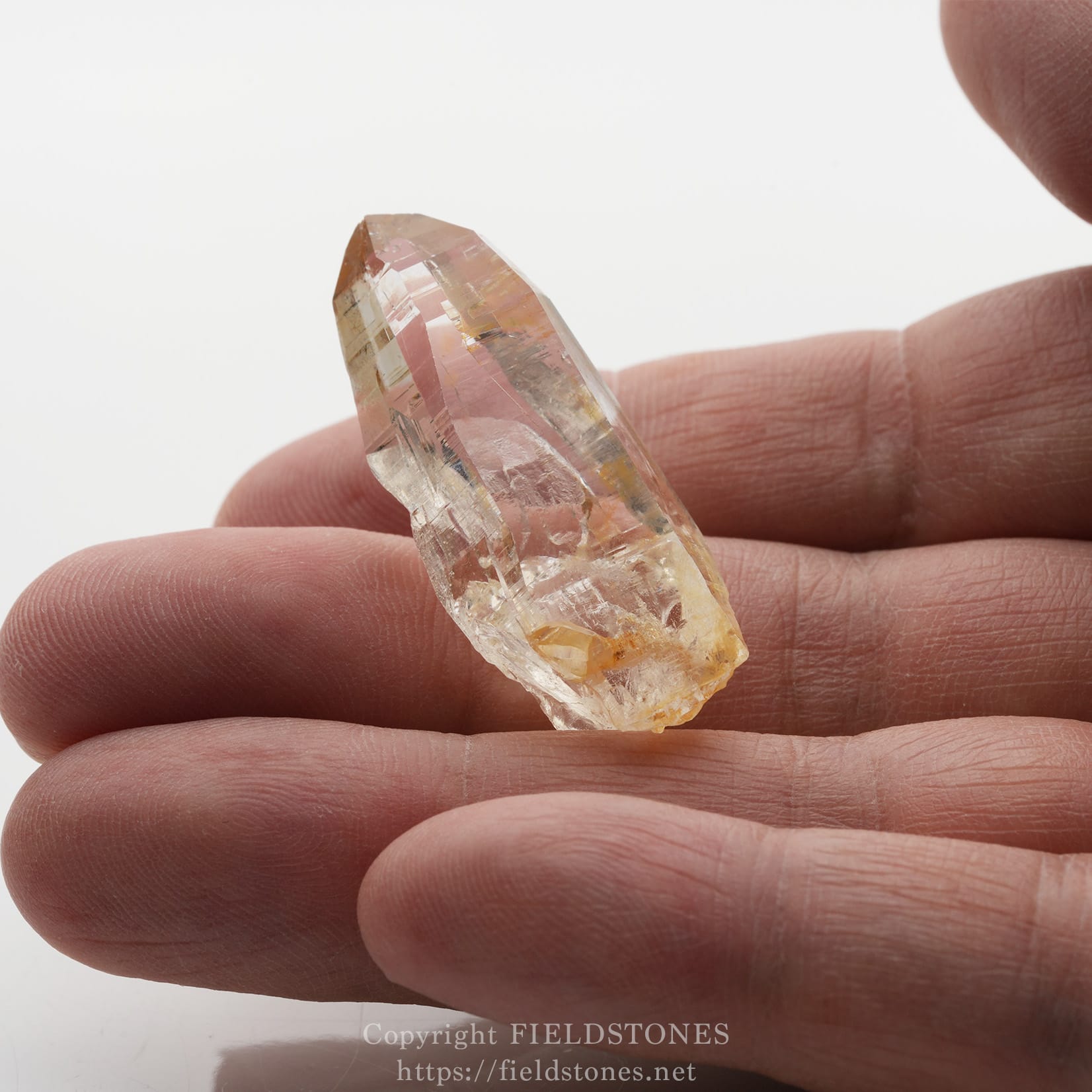 6506-12 - FieldStones Small pink rose quartz crystal being held between fingertips, showing translucent facets and natural inclusions.