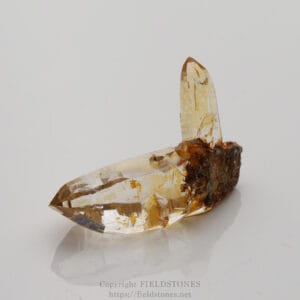 Clear quartz crystals embedded in a rusty brown rock matrix; translucent faceted prisms with sharp terminations.