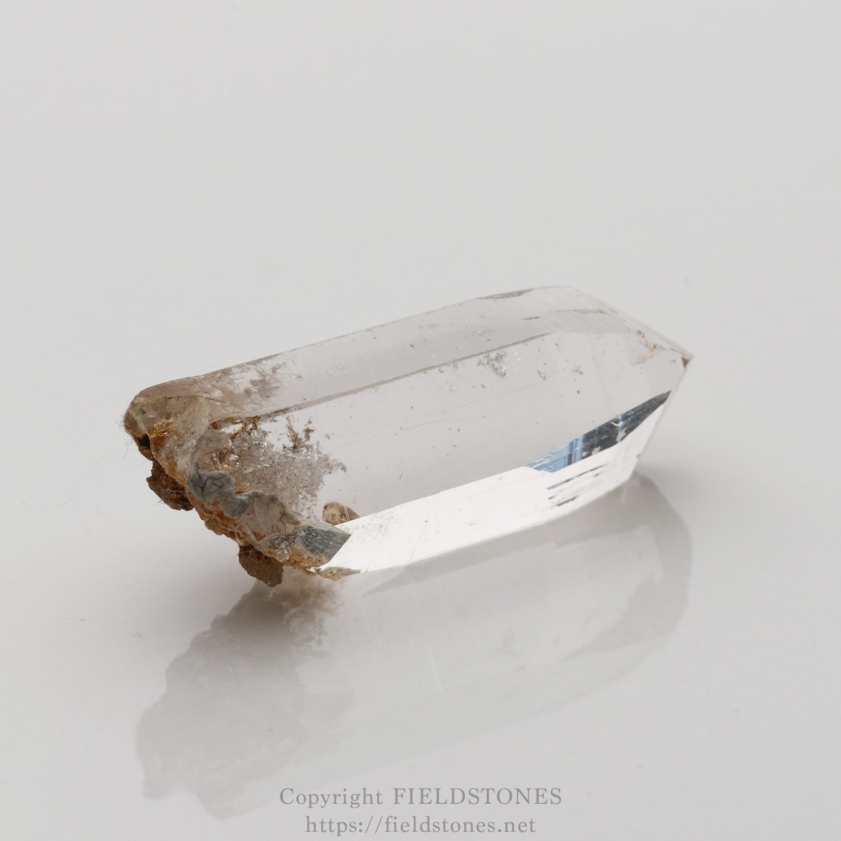 6508-3 - FieldStones Clear quartz crystal with a pointed termination and a rough, earthy base on a white background.