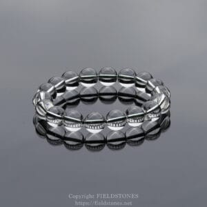 Clear glass bead bracelet on a reflective gray surface.