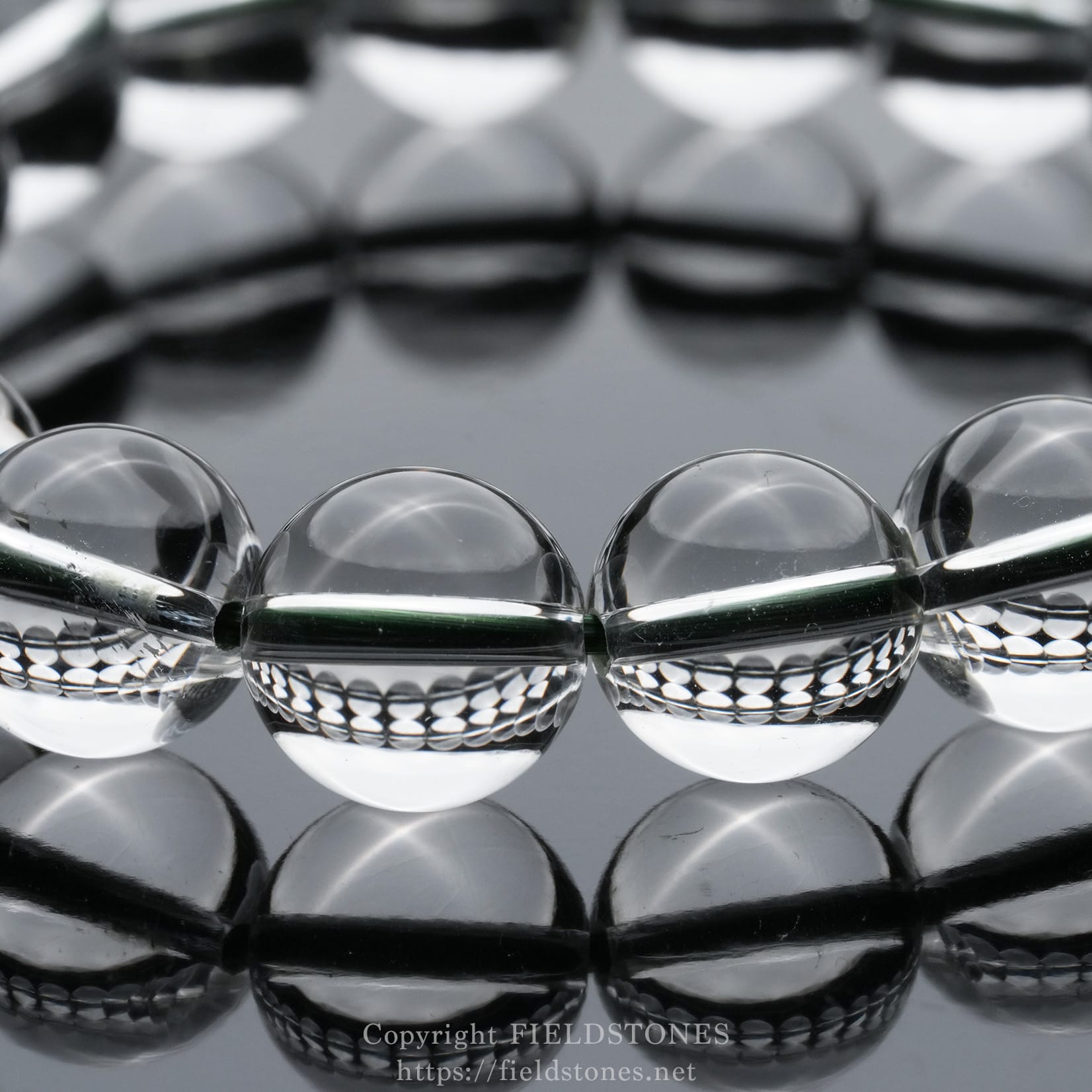 6512-10 - FieldStones Clear glass marbles lined up on a glossy reflective surface, creating a mirrored pattern and soft highlights.