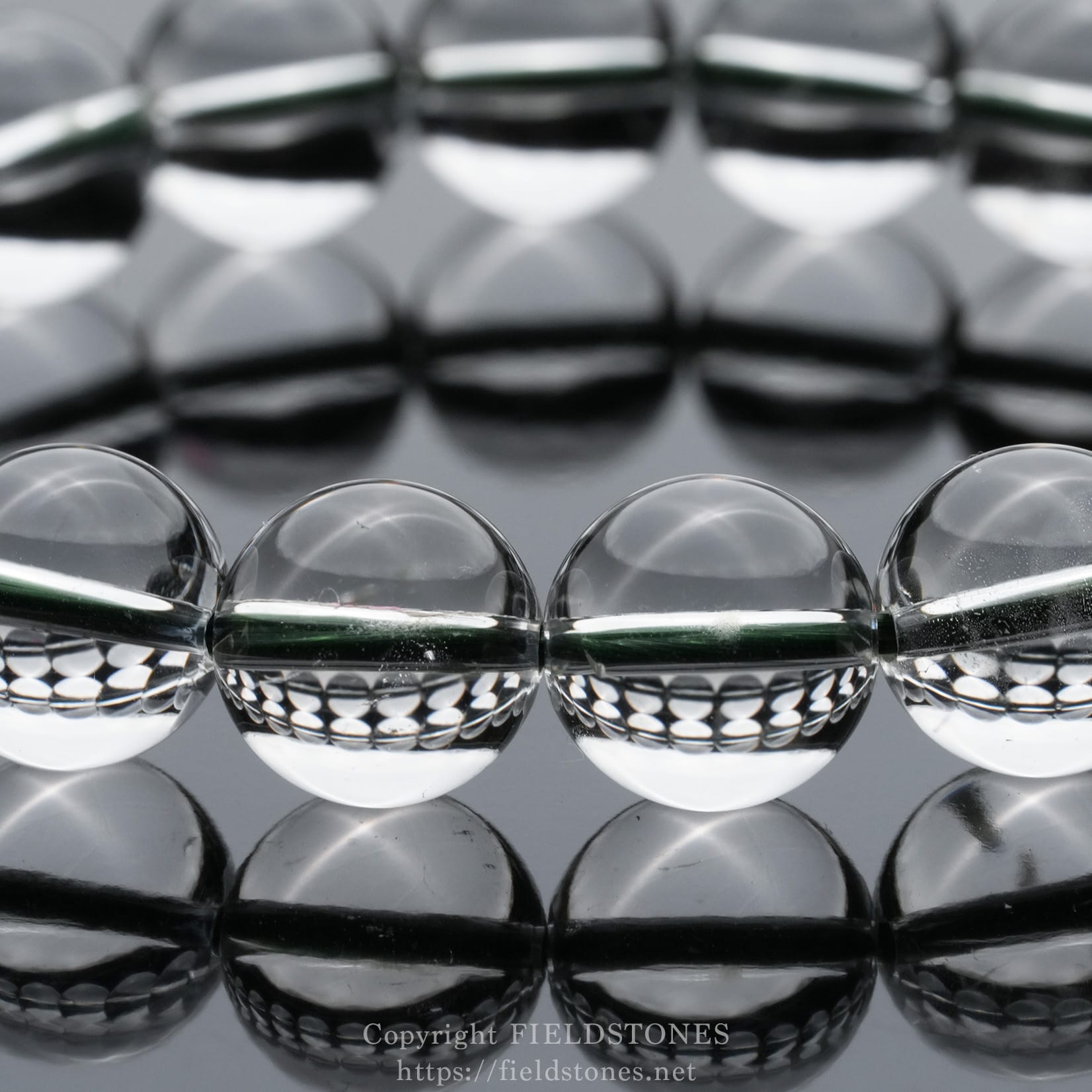 6512-11 - FieldStones Row of clear glass spheres on a mirrored surface creating reflections in a straight line: