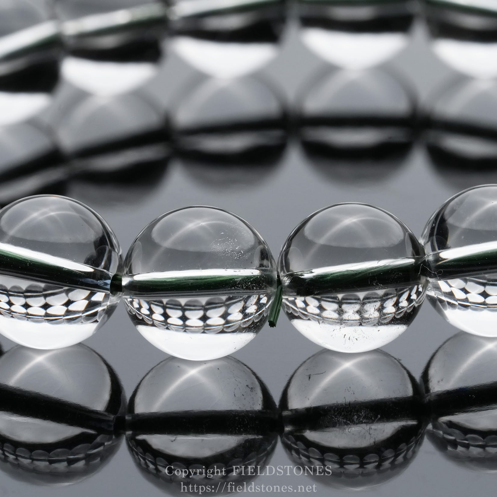 6512-9 - FieldStones Row of clear glass marbles on a highly reflective surface, creating mirrored reflections across the frame.