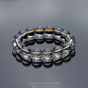Clear glass bead bracelet forming a circular loop on a reflective surface with a subtle watermark