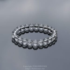 Clear glass bead bracelet resting on a reflective surface.