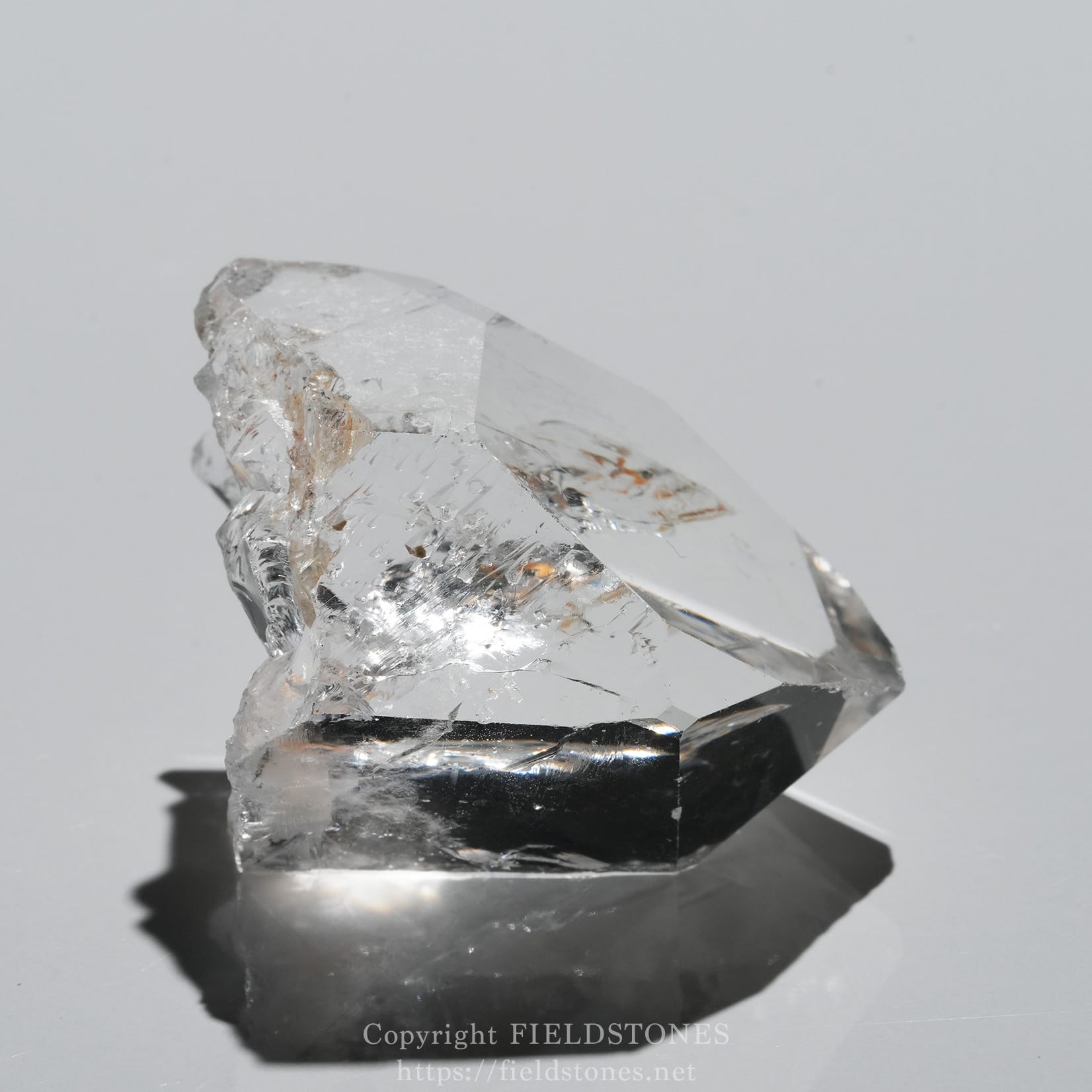 6571-2 - FieldStones Clear quartz crystal cluster resting on a dark base against a plain light background.