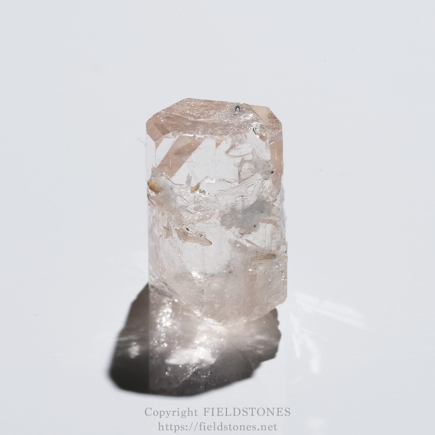 6576-12 - FieldStones Pale pink crystal prism standing upright on a white surface, casting a soft shadow.