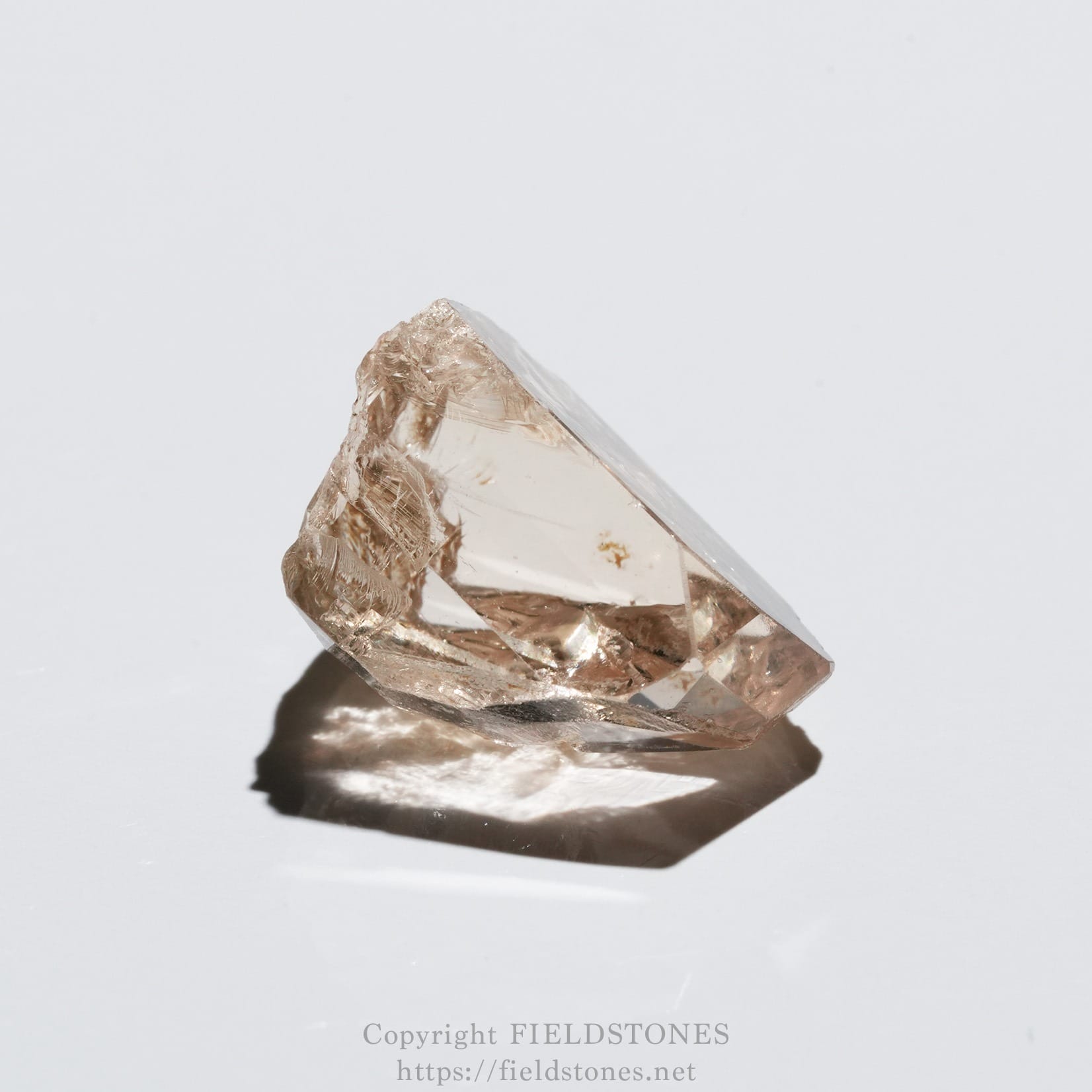 6578-10 - FieldStones Faceted rose quartz crystal on a white surface, showing pale pink facets and a soft shadow beneath.