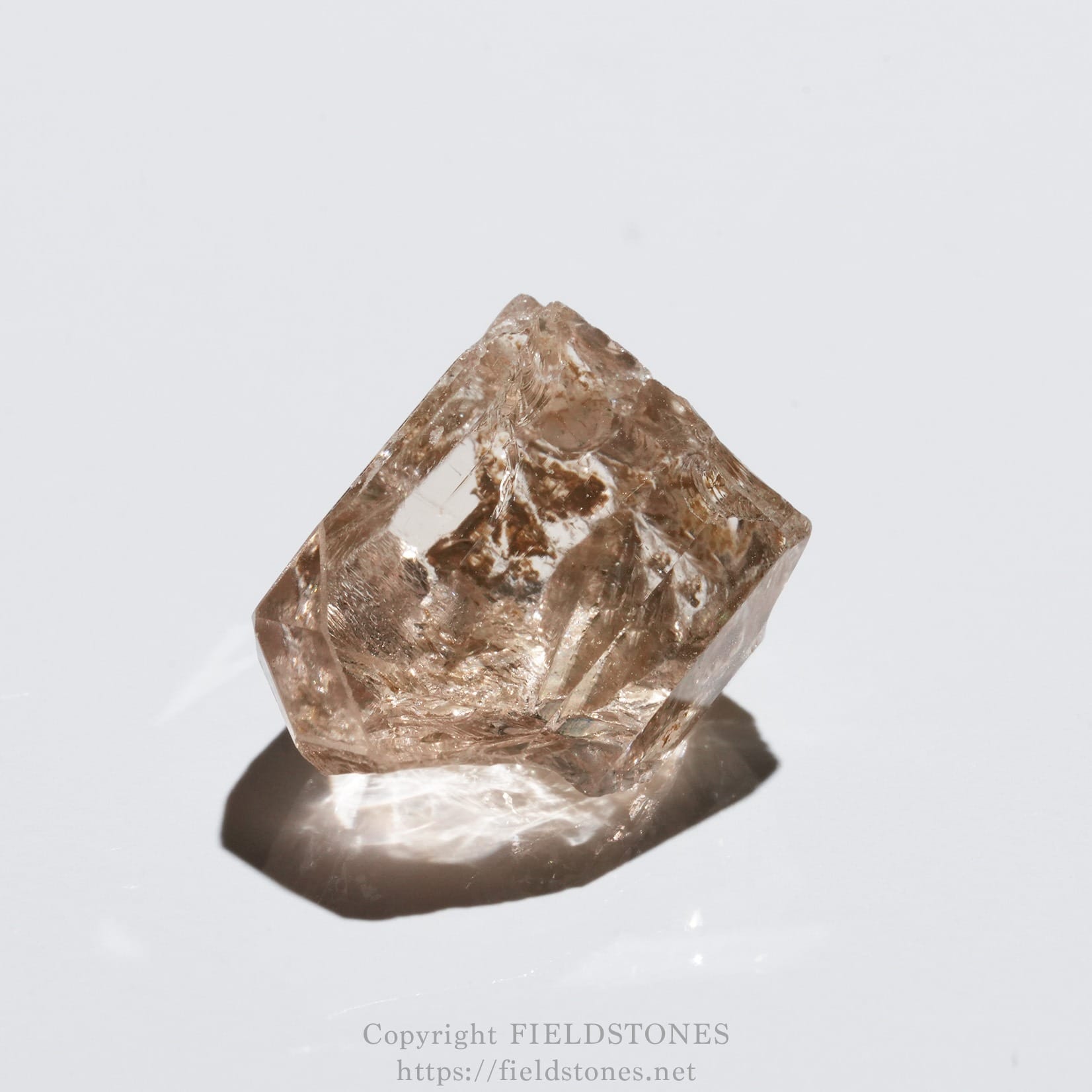 6578-11 - FieldStones Pink quartz crystal point resting on a white background, showing faceted edges and natural inclusions.