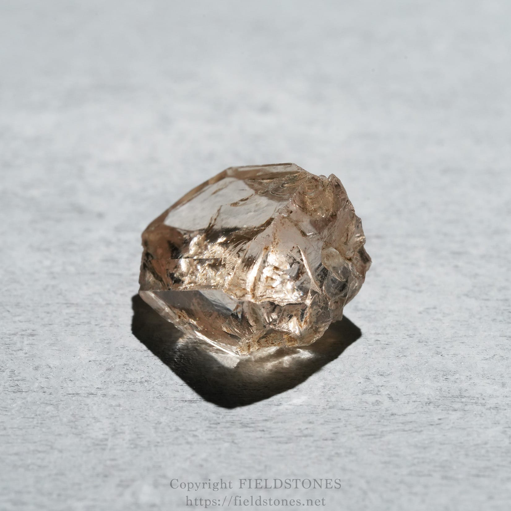 6578-5 - FieldStones Brownish quartz crystal on a light gray textured surface.