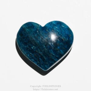 Polished blue gemstone carved into a heart shape on a white background with a subtle watermark at the bottom; decorative accessory piece.