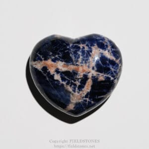 Polished blue marble heart stone with white and peach veins on a white background