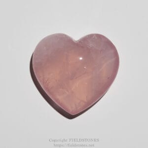 Polished pink rose quartz heart on a white background, close-up.