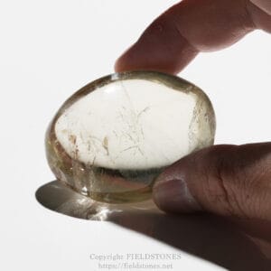 Close-up of a hand holding a smooth, translucent stone with visible internal cracks against a white background.