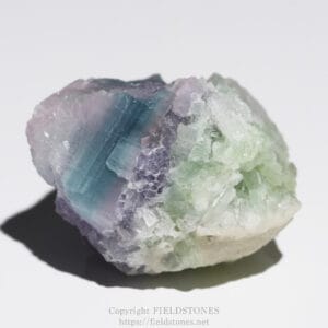 Pastel-colored crystal cluster with blue, purple, and green hues on a rough white base