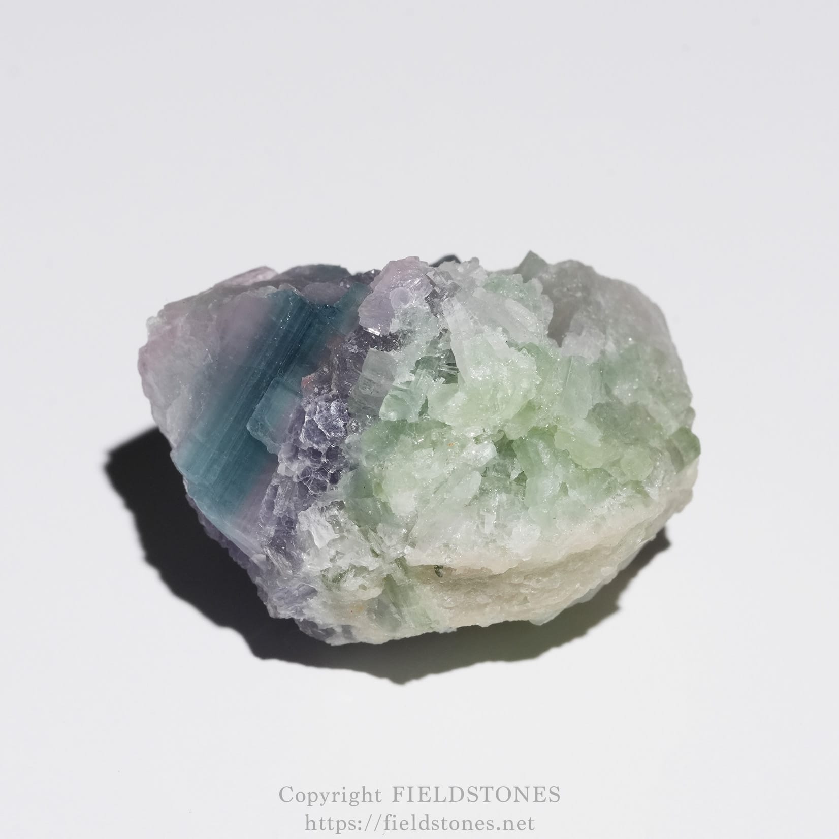 6645-5 - FieldStones Multi-colored fluorite crystal cluster in lavender, blue, and pale green tones on a white background.