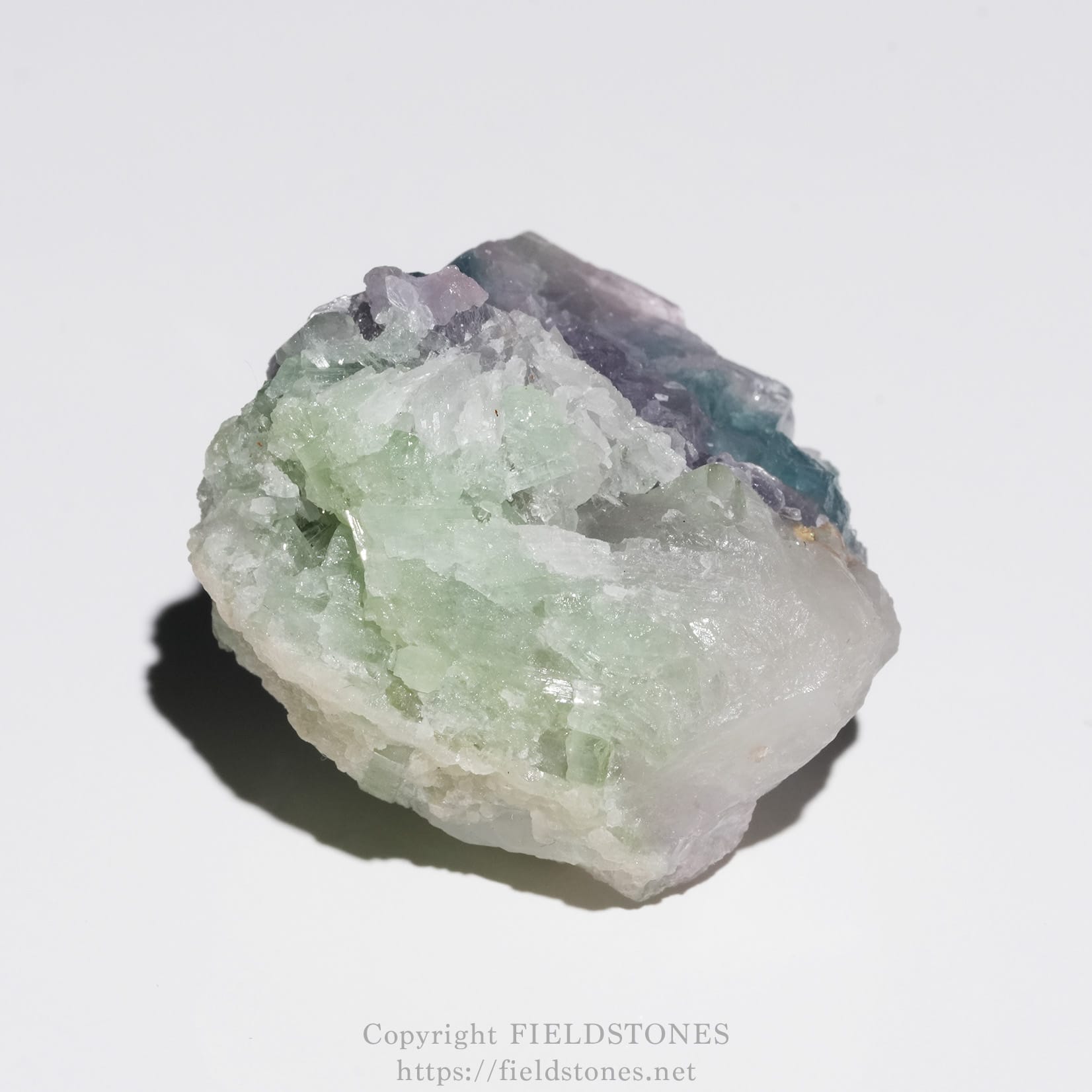 6645-6 - FieldStones Colorful fluorite crystal cluster with pale green, purple, and white facets on a white background.