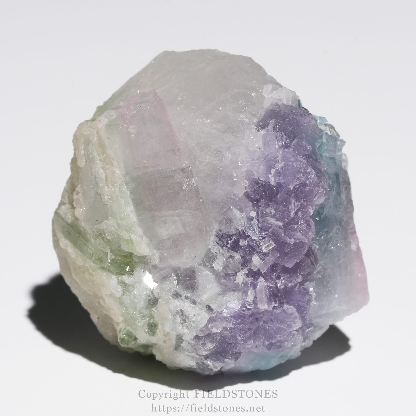 6645-9 - FieldStones Rough fluorite mineral cluster with pale purple, lavender, green, and blue crystals on a white background.