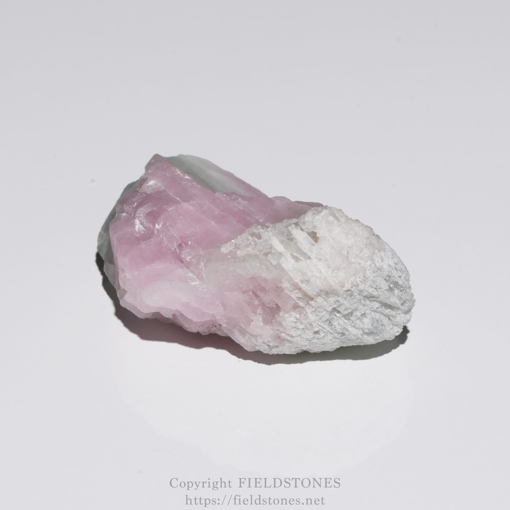 6652-8 - FieldStones Rough pink rose quartz crystal on a white background, showing its jagged edges and pale coloration.
