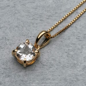 Gold pendant necklace with a large faceted clear gemstone on a gold chain, close-up view