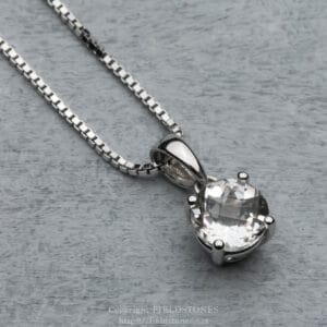 Silver necklace with a large faceted crystal pendant on a gray wooden surface.