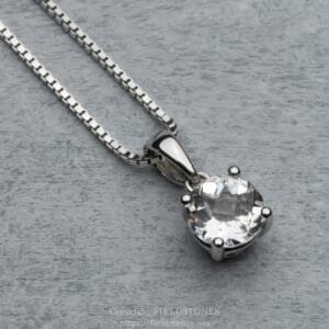 Silver chain necklace with a large clear round-cut crystal pendant on a gray wooden surface.