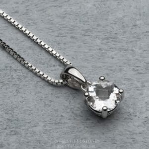 Silver necklace with a large, faceted crystal pendant resting on a gray wooden surface.