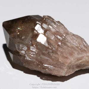 Close-up of a pink quartz crystal cluster with shiny, faceted faces on a pale background.