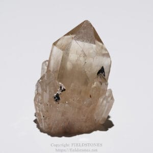 Pale brown quartz crystal cluster with translucent facets against a light gray background.