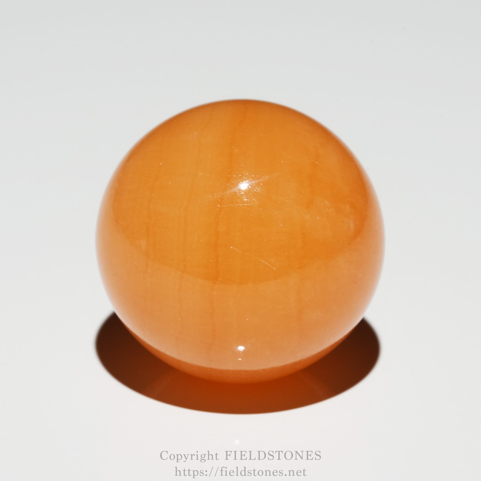 6676-3 - FieldStones Orange glossy wooden ball on a white background (close-up).