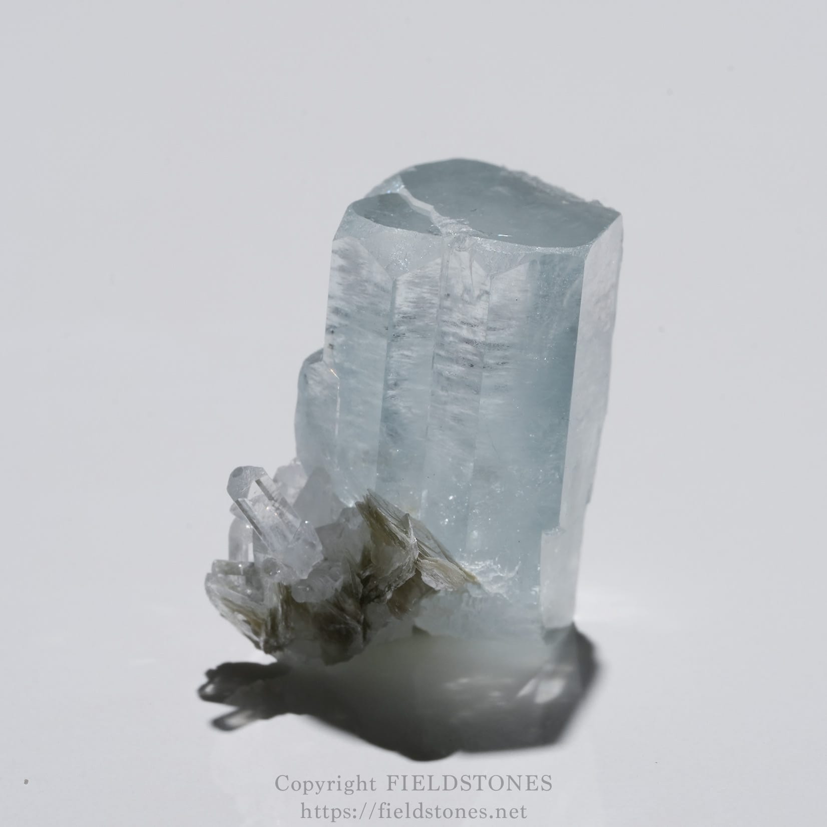 6690-2 - FieldStones Blue aquamarine crystal standing upright with clear, faceted faces on a white background.