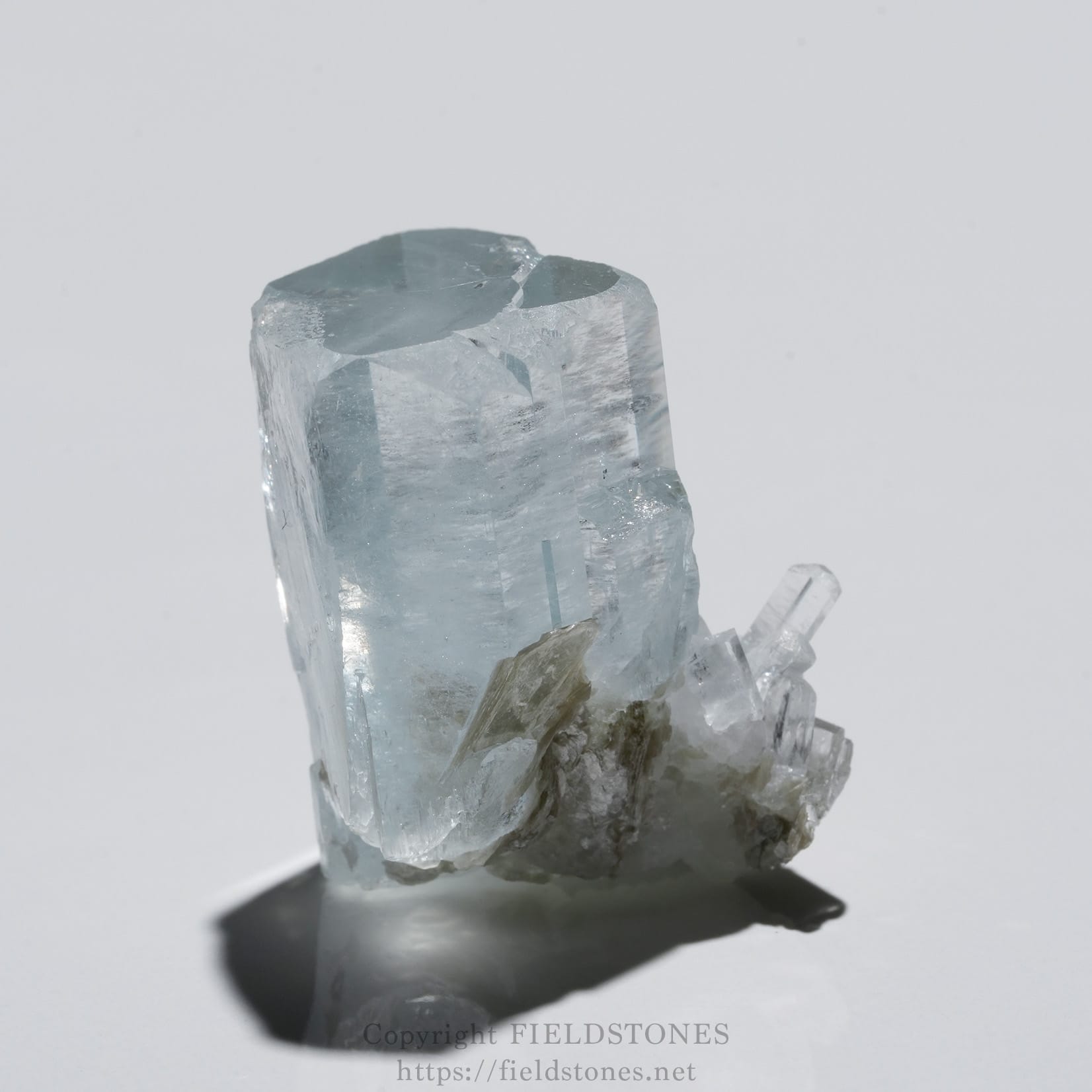 6690-6 - FieldStones Pale blue crystal cluster with translucent, faceted surfaces and a sharp terminus, resting on a dark base with a soft shadow beneath.