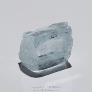 Close-up of a pale blue ice crystal with faceted edges on a white background to highlight its structure.