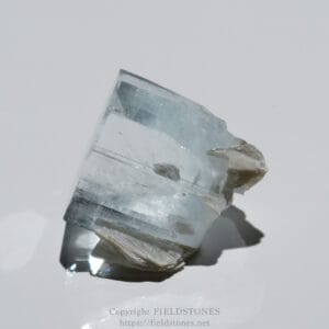 Translucent clear quartz crystal with faceted faces on a white background, tilted at an angle.