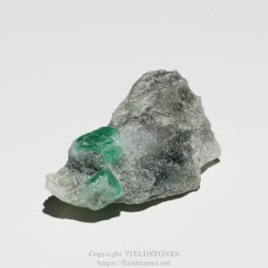 Rough gray rock with bright green crystals embedded, photographed on a white background