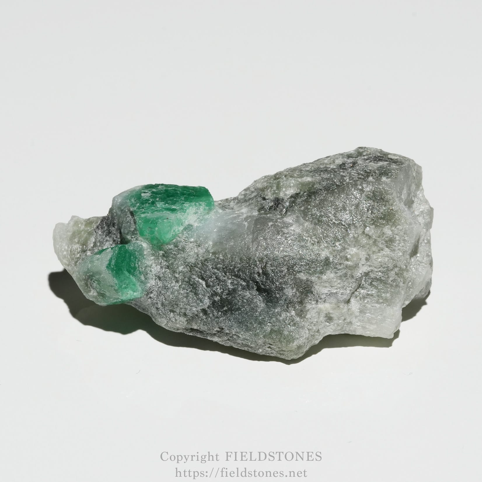 6696-2 - FieldStones Rough gray rock with bright green emerald crystals embedded in it.