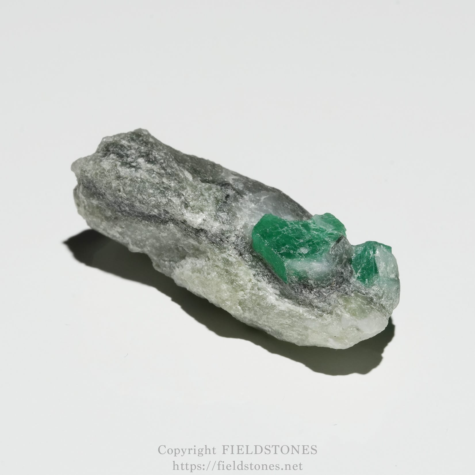 6696-6 - FieldStones Rough gray rock with bright green crystalline inclusions embedded in the surface.