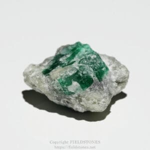 Rough rock matrix with bright green emerald crystals embedded in gray stone.