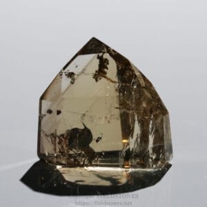 Large smoky quartz crystal with brown inclusions, standing on a glossy surface.