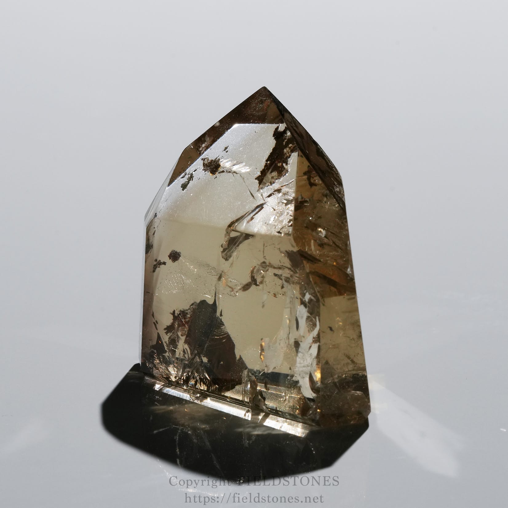 6708-2 - FieldStones Brown-tinted crystal quartz standing upright on a base, with visible internal inclusions and facets catching light.