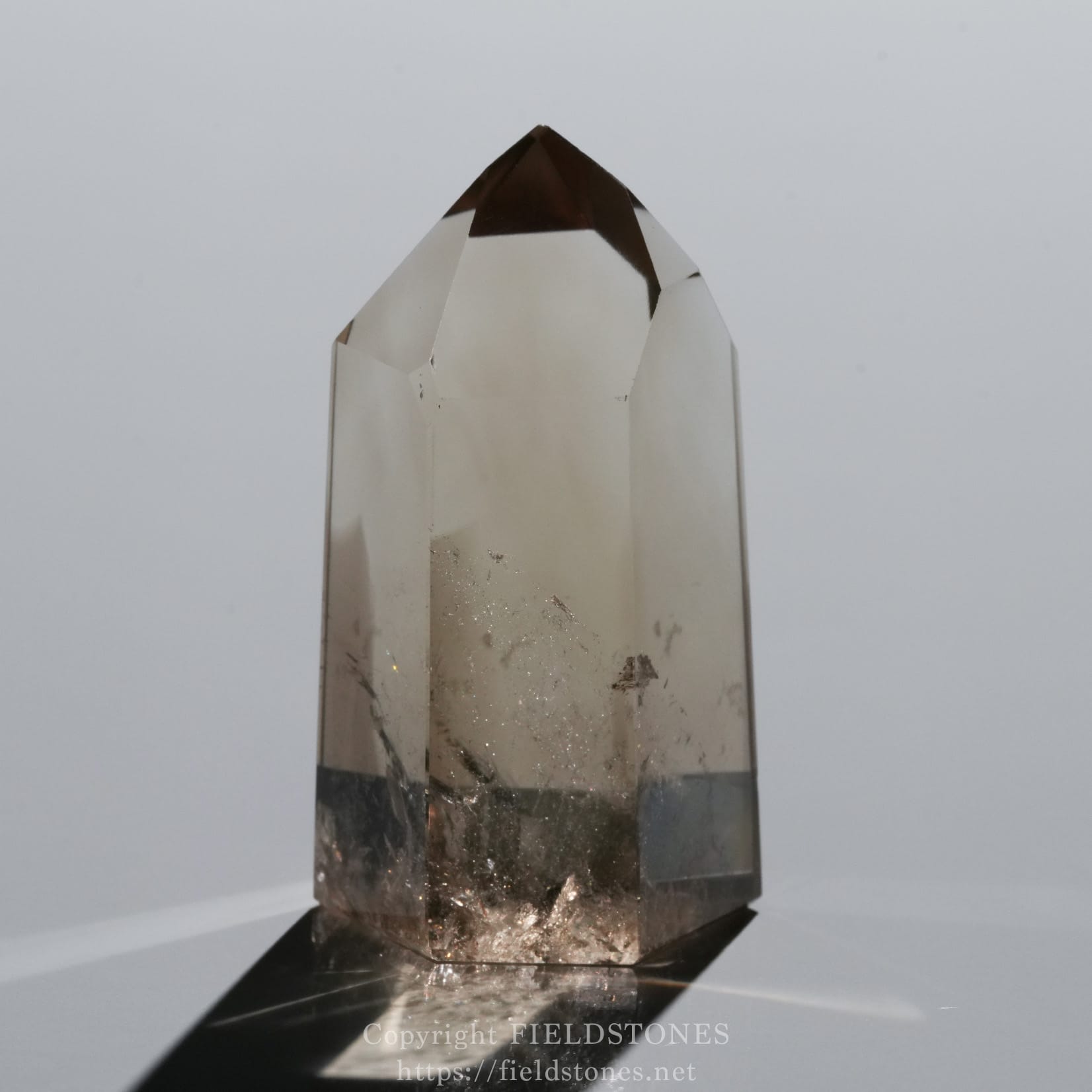 6709-3 - FieldStones Clear quartz crystal obelisk with a pointed tip, mounted on a dark base against a light background.