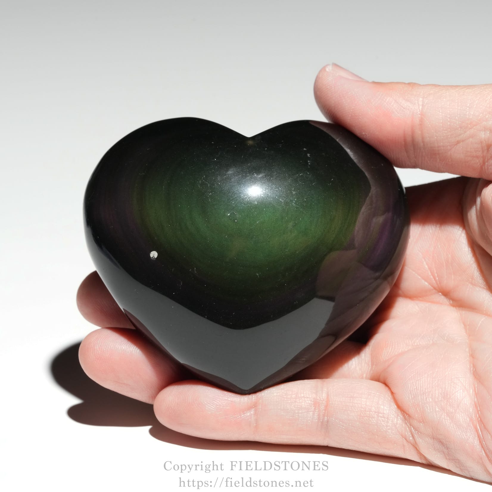 6711-3 - FieldStones Polished dark green heart-shaped stone being held between fingers.