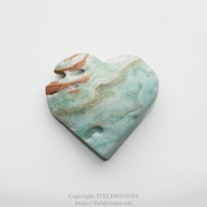 Polished heart-shaped stone with green, blue, and brown marbling on a light background.