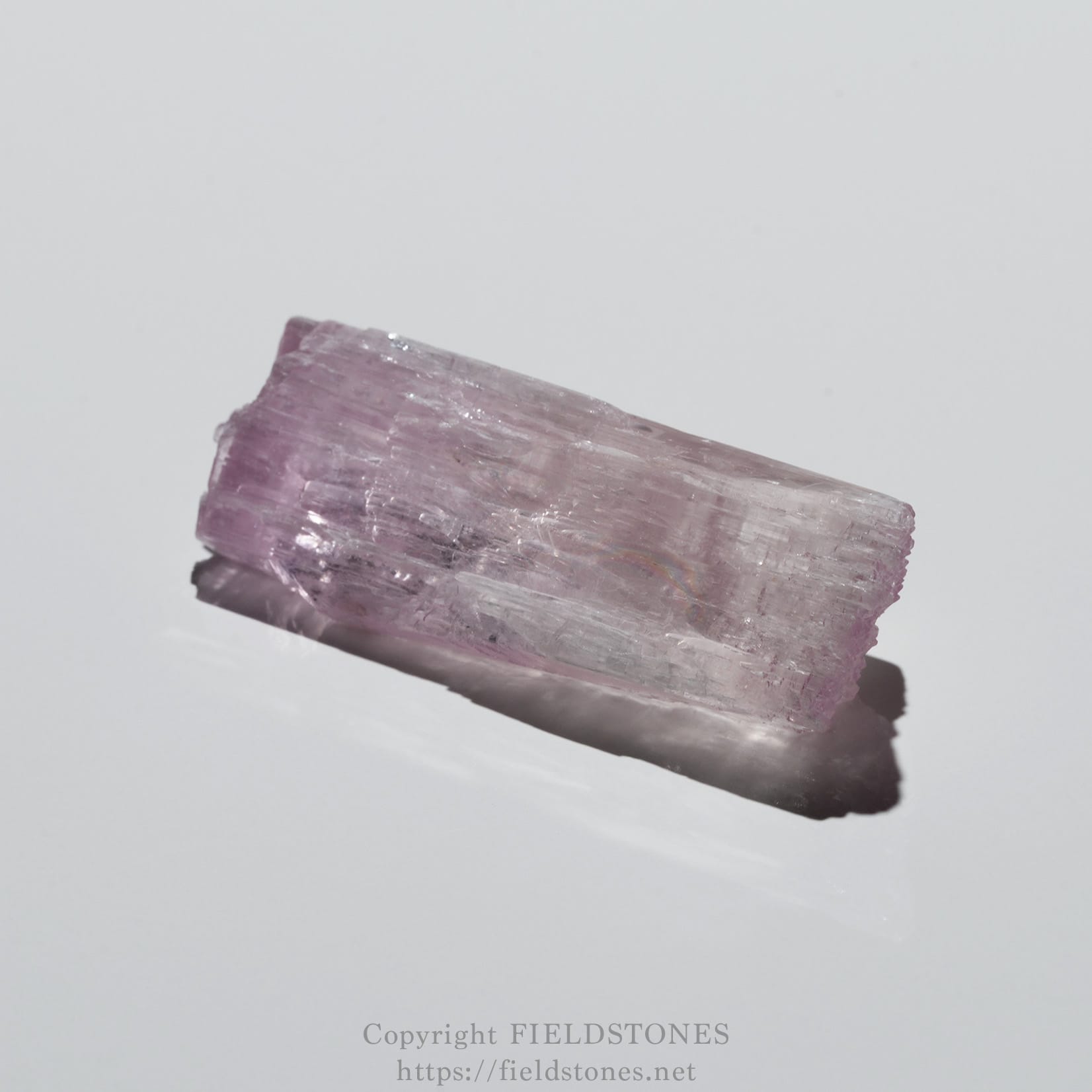 6726-6 - FieldStones Pink rectangular crystal with rough, glistening facets photographed on a white background.
