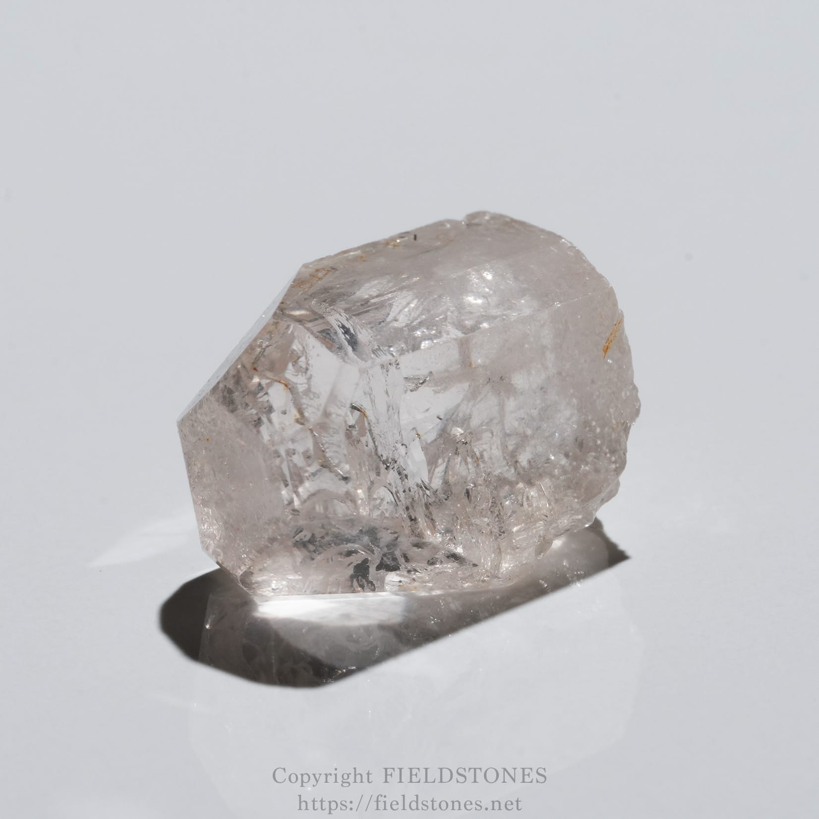 6737-9 - FieldStones Translucent quartz crystal with jagged facets resting on a white surface.