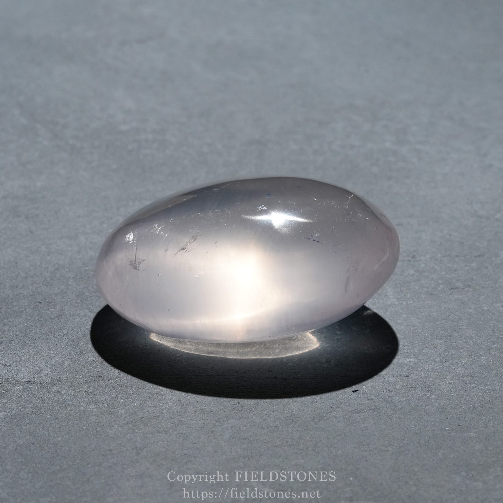 6740-9 - FieldStones Polished metallic-looking stone resting on a dark surface with a soft shadow beneath it.