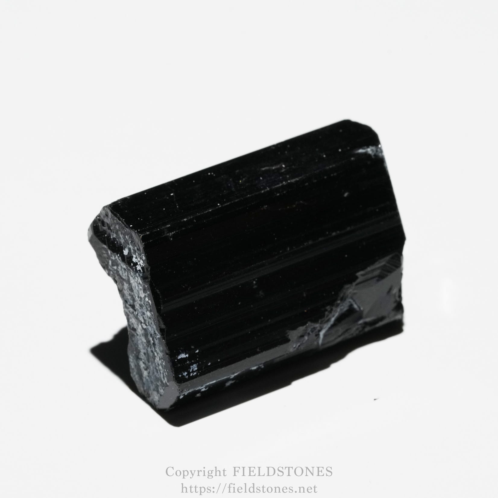6748-6 - FieldStones Macro photo of a black, rectangular mineral crystal with rough, jagged edges on a white background