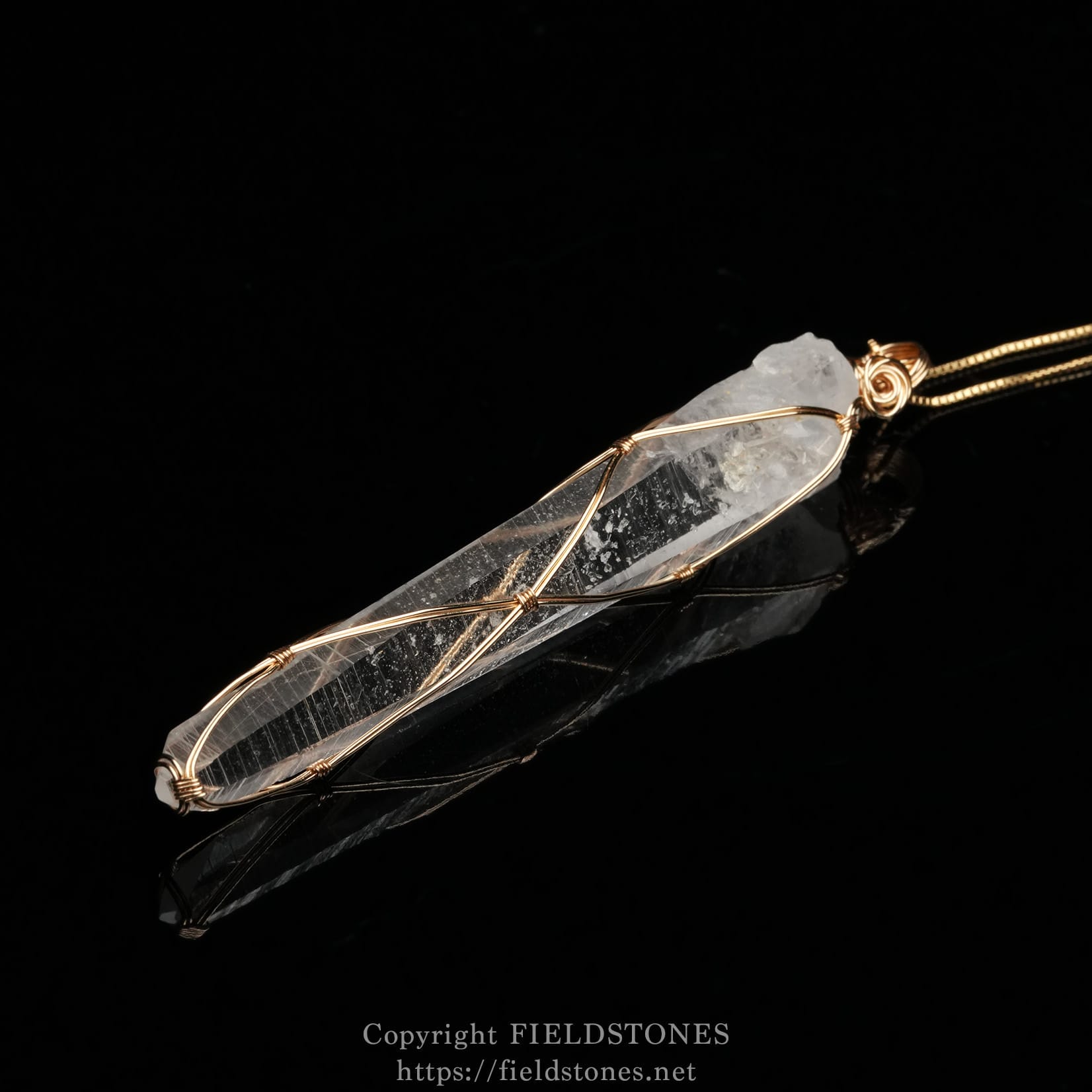6751-1 - FieldStones Clear quartz crystal pendant wrapped in copper wire on a black background, hanging from a thin chain.