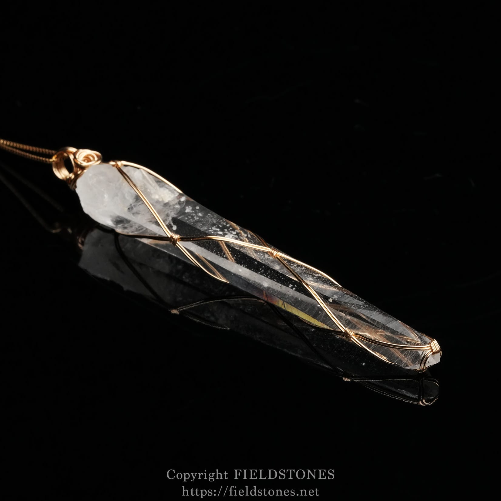 6751-2 - FieldStones Copper-wire wrapped clear quartz pendant resting on a black background