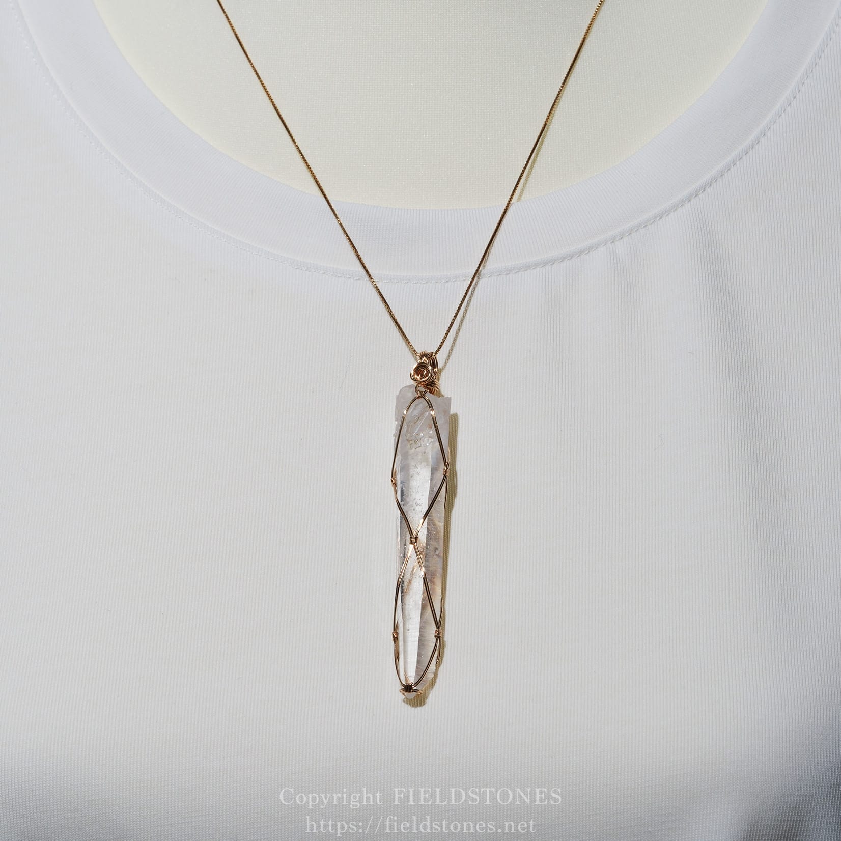 6751-7 - FieldStones Gold wire-wrapped crystal pendant on a thin gold chain resting on a white shirt neckline.